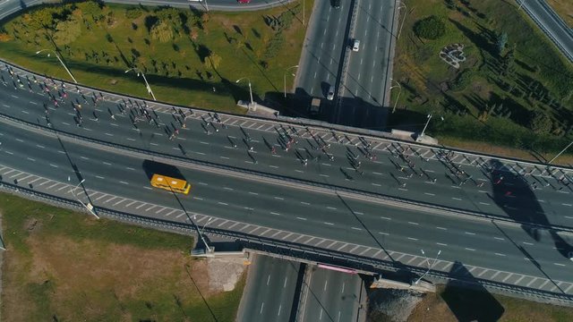 Aerial drone footage. Fly around marathon running on the road junction top view