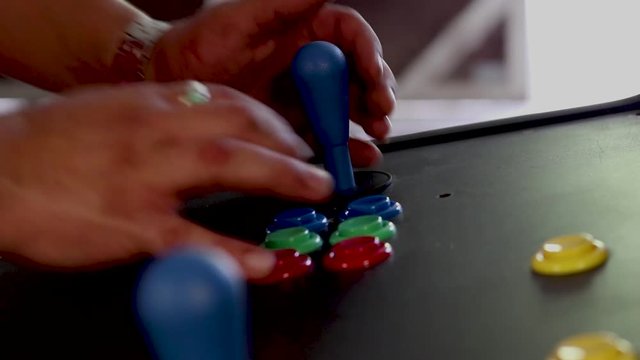 A SLOWMOTION side view close up shot of a man playing video game by controlling joystick and pressing various buttons with his hands