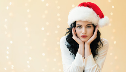 Young woman with a Santa hat on a shiny light background