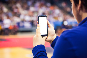 Hands using mobile phone in front of red carpet and crowd