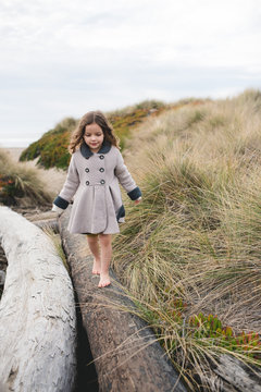Vertical orientation of child walking across a log at the beach