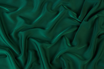 Green silk fabric background, view from above. Smooth elegant green silk or satin luxury cloth texture can use as abstract background with copy space. 