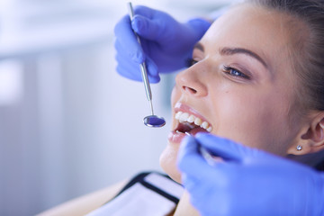 Young Female patient with open mouth examining dental inspection at dentist office.