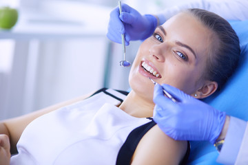 Fototapeta premium Young Female patient with open mouth examining dental inspection at dentist office.