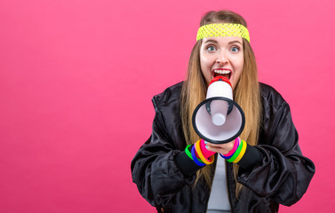 Woman in 1980's fashion holding a megaphone on a pink background
