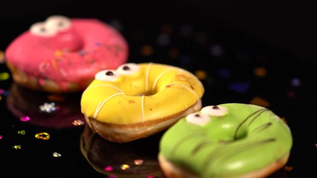 Three spinning colorful iced ring donuts