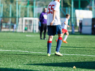 Obraz premium football teams - boys in red, blue, white uniform play soccer on the green field. boys dribbling. dribbling skills. Team game, training, active lifestyle, hobby, sport for kids concept