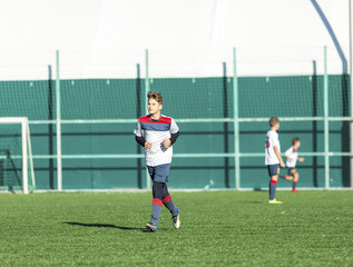football teams - boys in red, blue, white uniform play soccer on the green field. boys dribbling. dribbling skills. Team game, training, active lifestyle, hobby, sport for kids concept