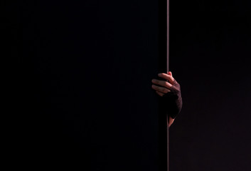 Female hand in black gloves holds edge of wall. Black background. Close-up. Theme for the design of the holiday Halloween. Mysticism, horror and fear. Copyspace.