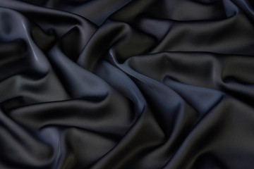 Black silk fabric background, view from above. Smooth elegant black silk or satin luxury cloth texture can use as abstract background with copy space, close-up 