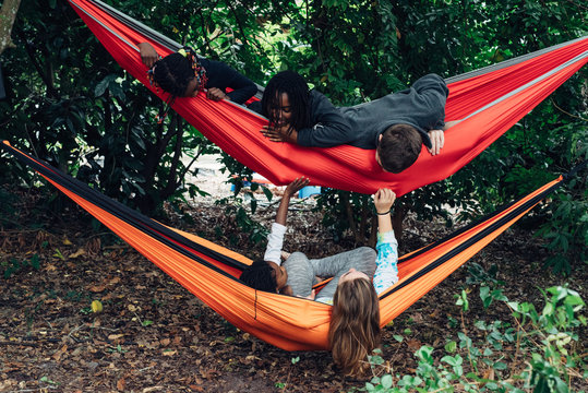Black and Caucasian kids chilling out in colorful hammocks