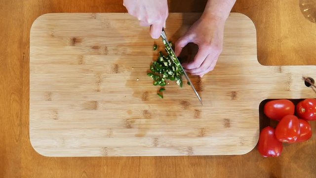 Dicing jalapeno peppers on cutting board, close up