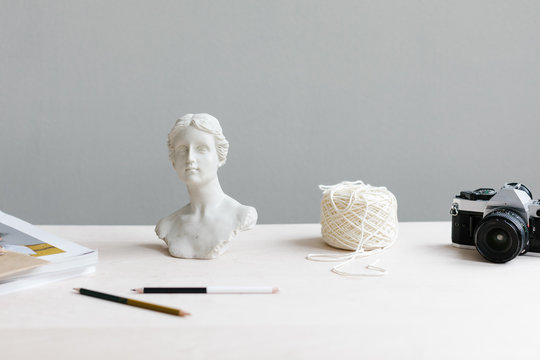 artist's desk with statue of woman, yarn and camera