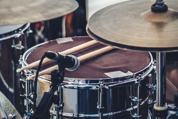 Snare drum with microphone and drumsticks, surrounded by cymbals