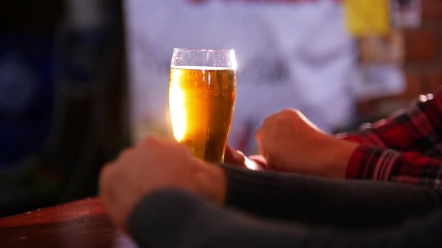 Guys talking in the pub, guy takes a sip of beer and puts it back on the bar counter