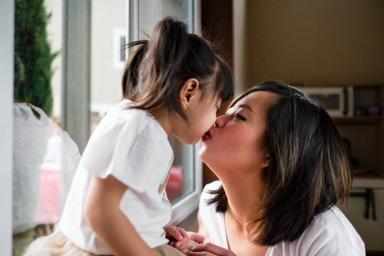 Asian Mother Kissing Her Daughter at Home