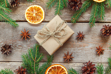 Obraz na płótnie Canvas Christmas New Year composition with gift box fir branch pine cones orange slices on old shabby rustic wooden background Xmas holiday december decoration. Flat lay top view Time for celebration concept