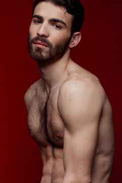 Handsome shirtless strong man portrait over red background