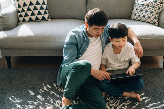 Father and son using laptop at home