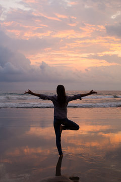 Woman silhouette yoga practicing on the beach