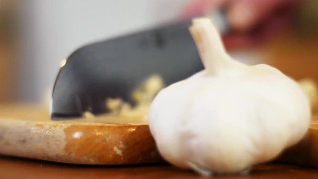 Mincing garlic on cutting board, close up