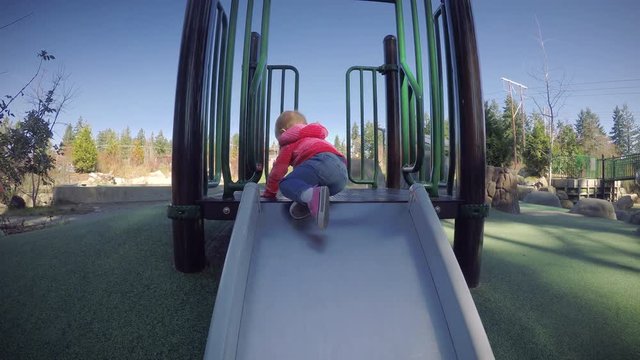 Toddler Turning Backwards Down Park Slide