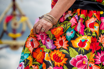 Mujer oaxaqueña con falda bordada y mano con pulsera de oro y anillos bailando en la guelaguetza 