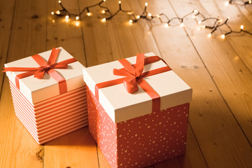 red gift boxes and christmas lights on wooden floor