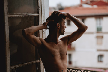 handsome man bare chest posing on a window