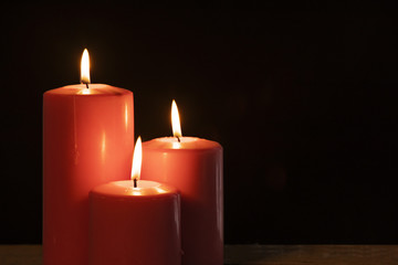 Fototapeta na wymiar Three burning candles with dark background