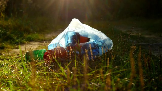 A package of plastic garbage lies in the forest on a forest road, pollution of nature, garbage and nature, the sun, close-up