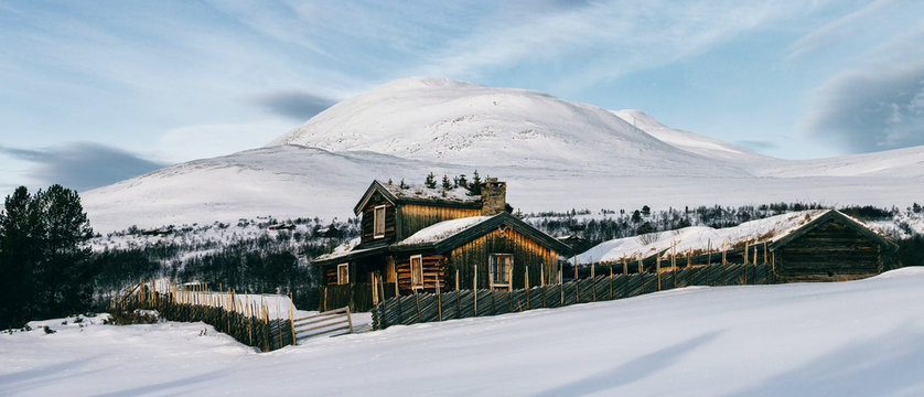 Rustic Wooden Log Cabins in Nordic Winter Landscape