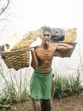Man in volcano crater carrying minerals
