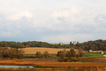 Fototapeta na wymiar Wisconsin autumn nature background. Autumn rural landscape with farms scattered among forested hills and fields and cloudy sky over. Typical Wisconsin countryside view, Midwest USA.