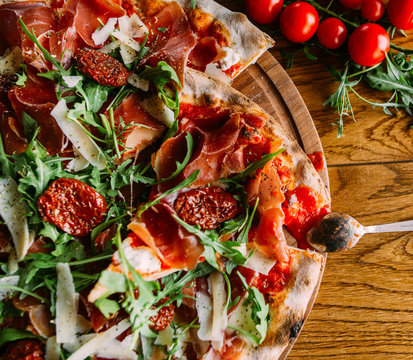 Large pizza topped with mozzarella,  ham,  tomatoes, shallot and fresh herbs
