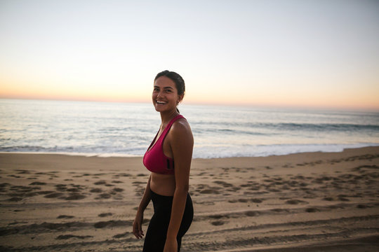 Fit woman running and working out on the beach at sunset