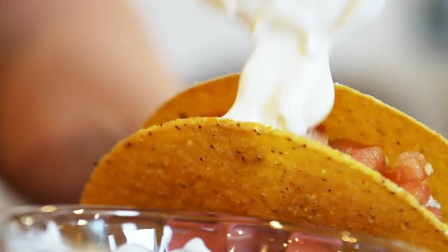 Adding sour cream to taco shell, close up