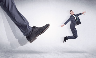 Boss mobbing his worker, illustrated by black shoe kicking small businessman who is flying away in...