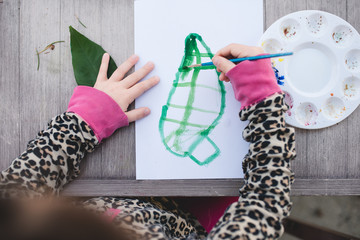 Child learning about photosynthesis and painting a green leaf