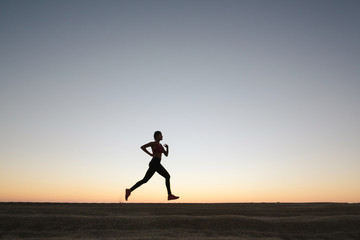 Obraz premium Fit woman running and working out on the beach at sunset