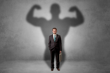 Obraz premium Lovely serious businessman standing with a muscular powerful shadow behind his back 