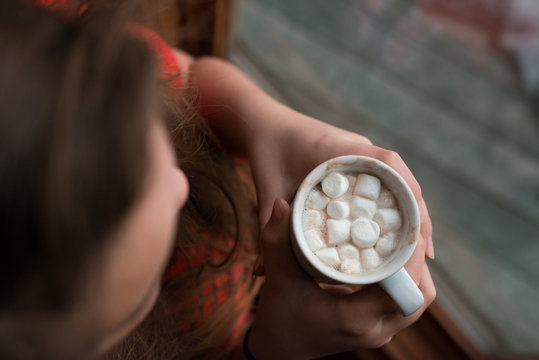 Woman warming up in ski chalet with mug of hot chocolate
