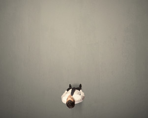 Young businessman contemplating a decision standing on a grey surface