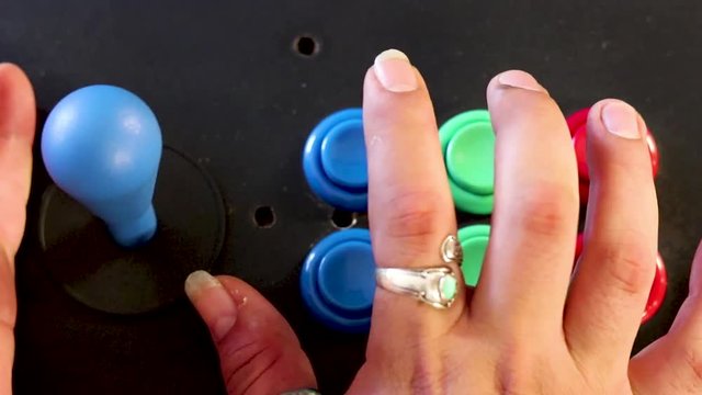 A realtime over head close up shot of a man playing video game by controlling joystick and pressing various buttons with his hands