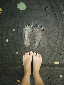 Crop feet on wet concrete with footprints