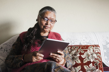 Elderly south asian woman using a tablet computer.