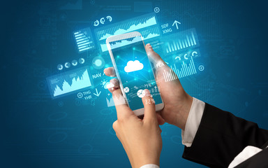 Female hand using smartphone with financial tracking concept illustrated by graphs and symbols