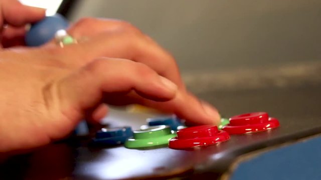 A realtime side view close up shot of a man playing video game by controlling joystick and pressing various buttons with his hands
