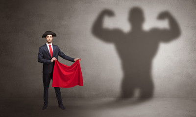 Fototapeta premium Businessman standing with red cloth on his hand and strong hero shadow on the background 