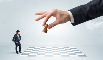 Little businessman thinking about chess strategy with a big hand concept
